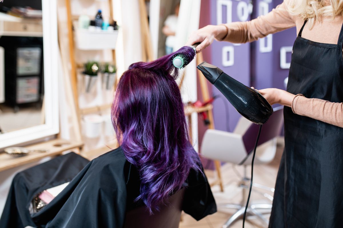 Woman with purple hair getting a blow dry at the salon