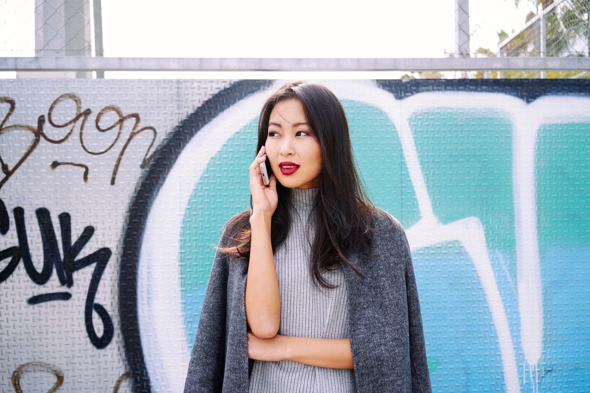 Stylish Filipino woman wearing an outfit in different shades of gray, talking on the phone