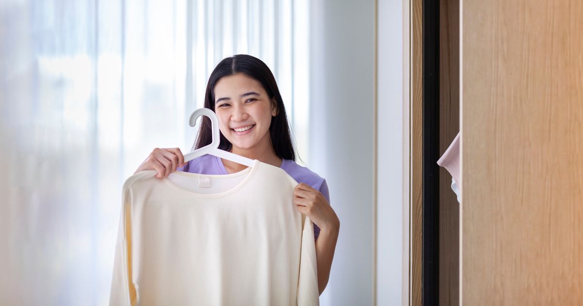 Filipino woman smiling while holding beige top on hanger