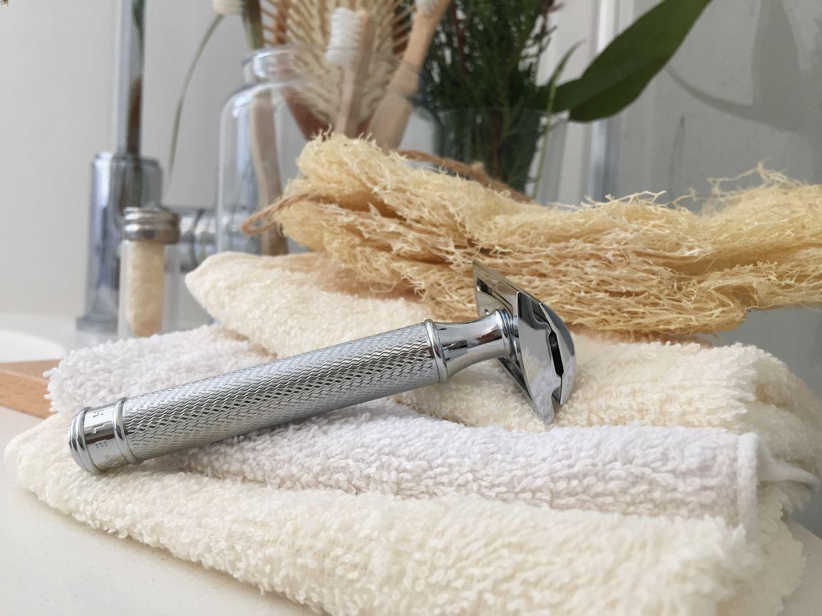 A shaving razor lies on a stack of towels. 