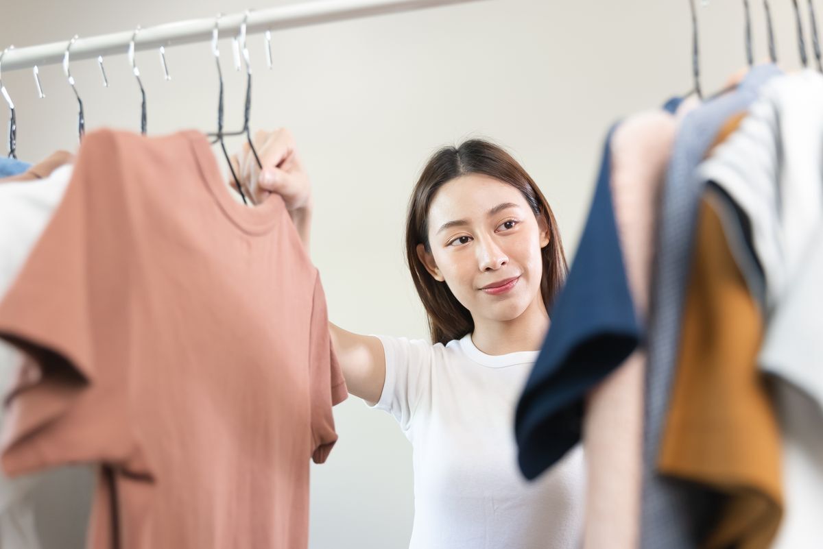 Asian woman looking at clothes in closet