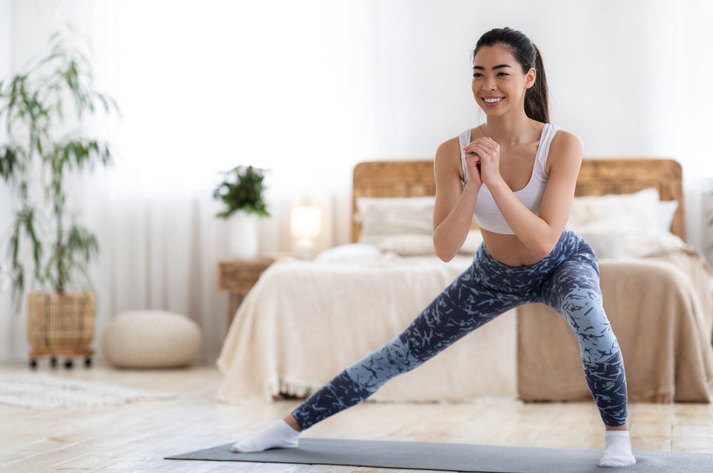 Asian woman doing lunges at home on an exercise mat. 
