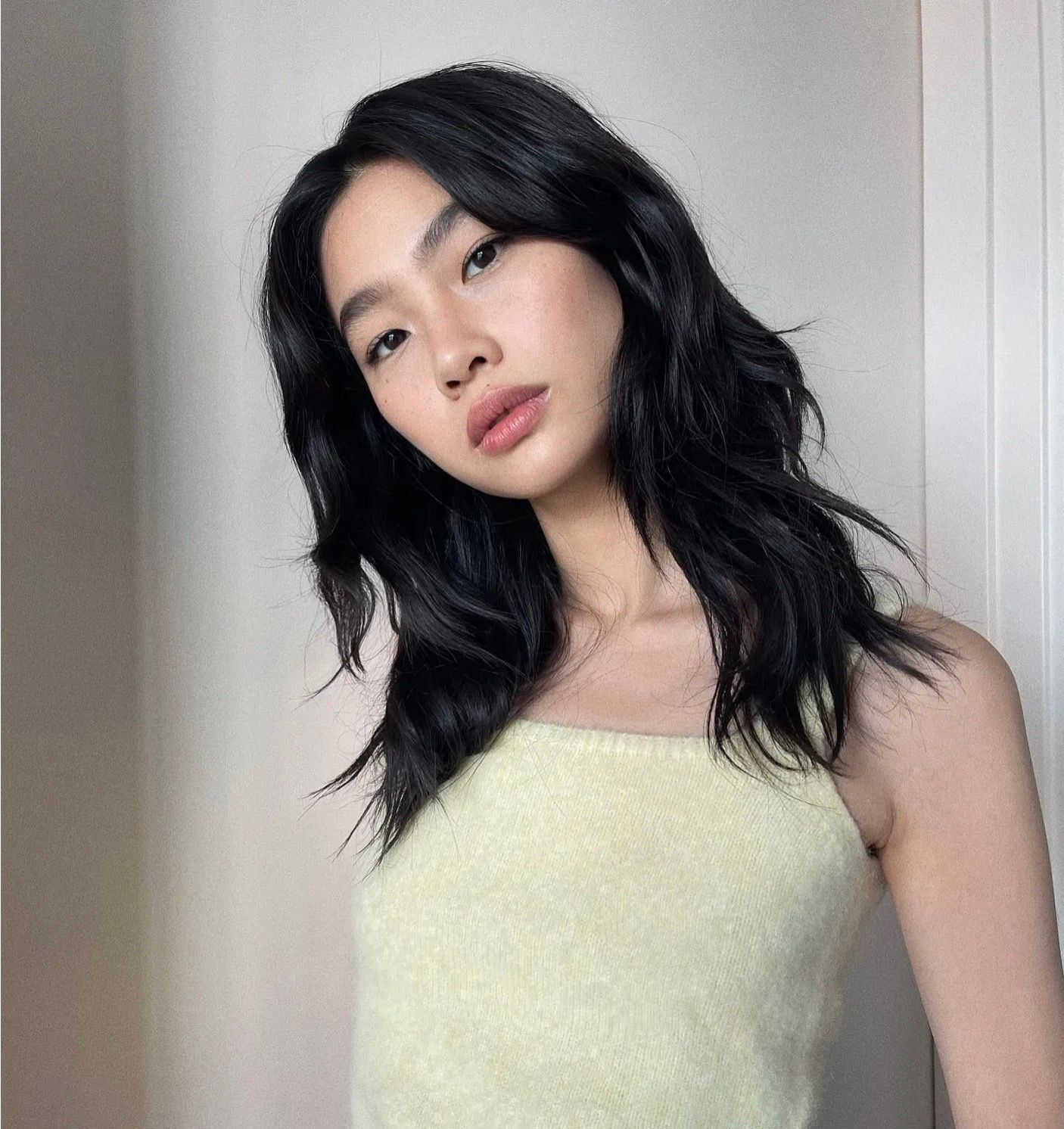 Young Asian girl with wavy hair against a white background. 