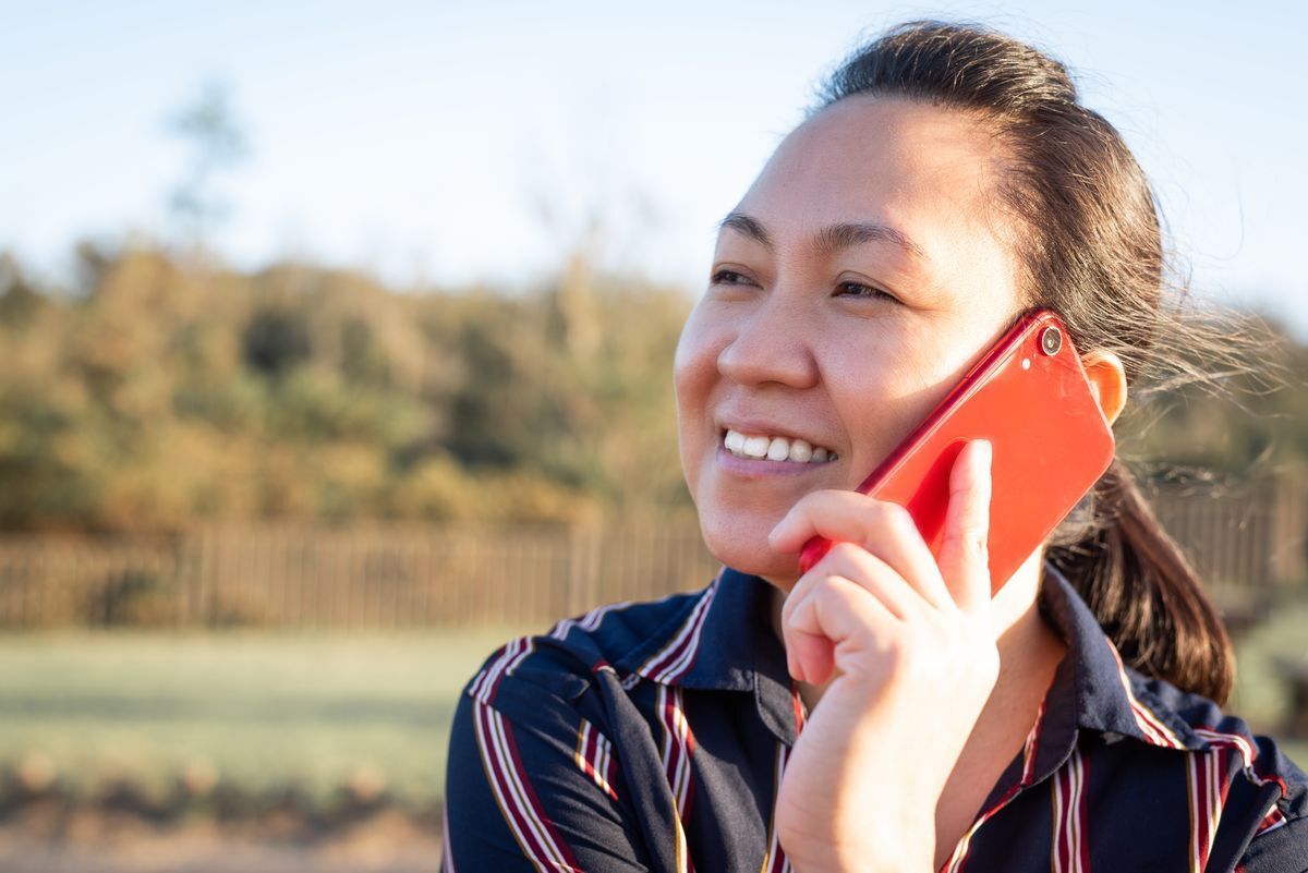 Filipino woman talking on the phone under the sun