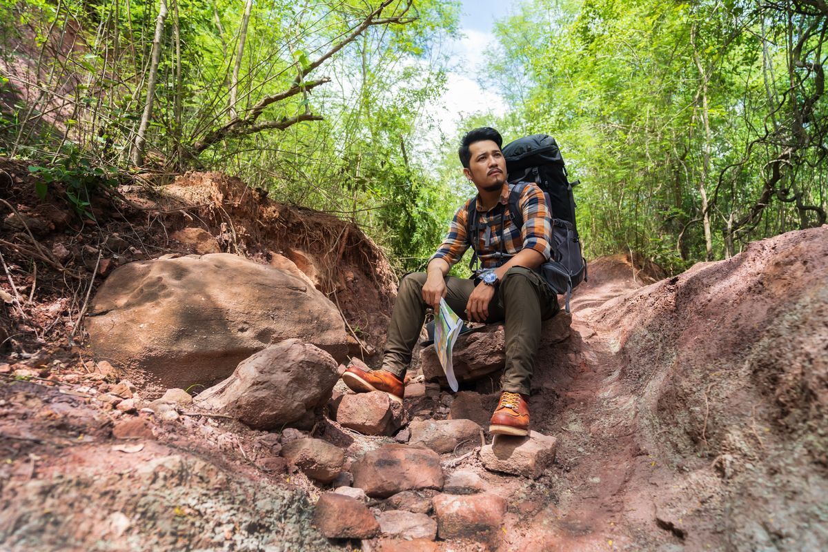 Filipino man sitting on rocks in the woods.