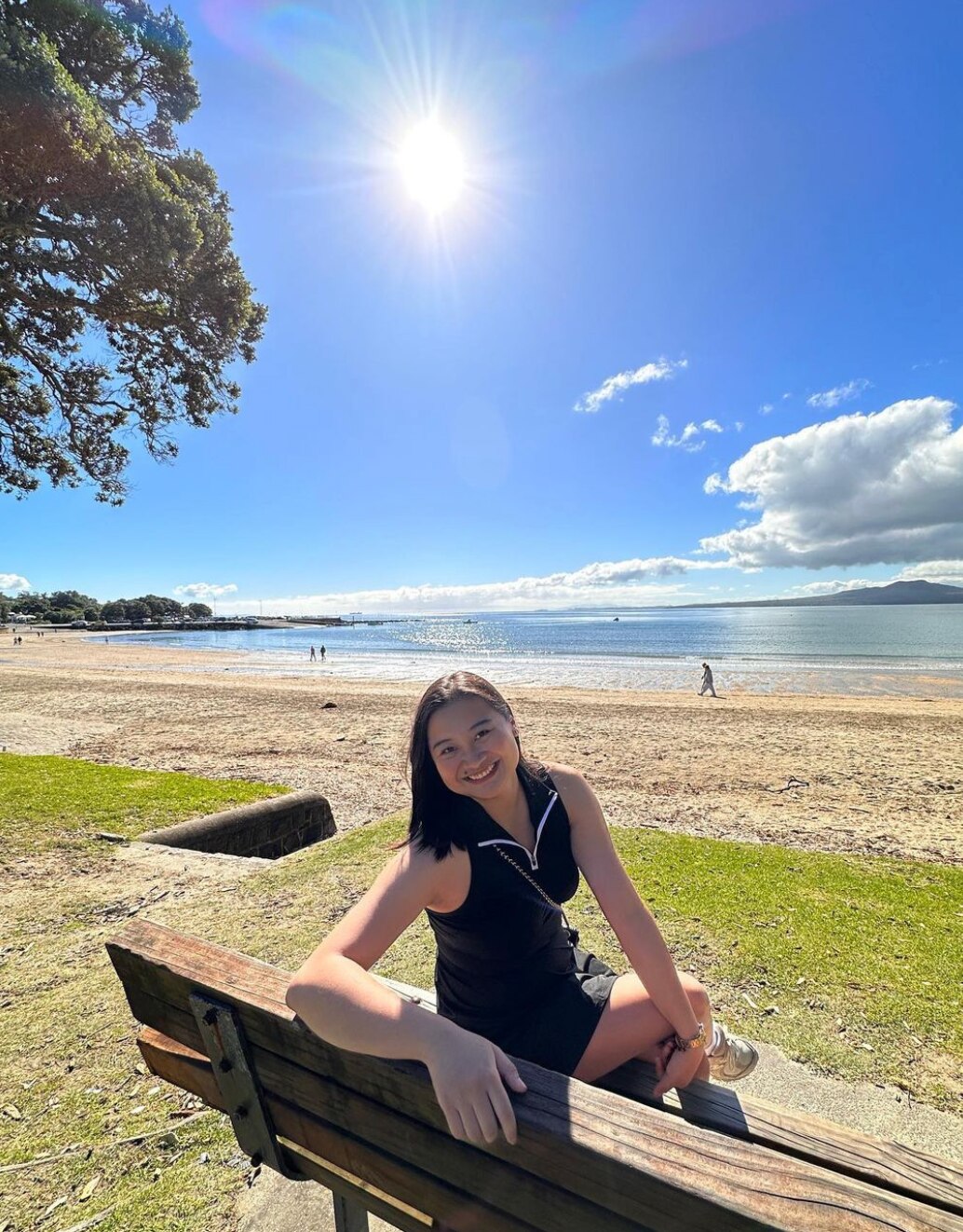 Woman sitting on a bench at the beach on a sunny day. 