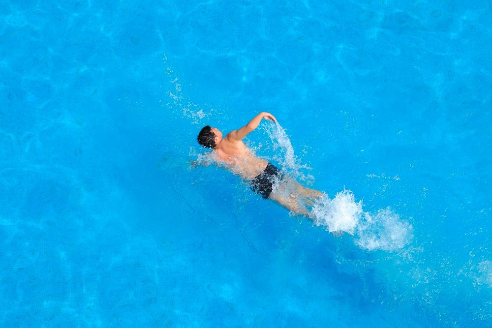 Top shot of man swimming on blue water.