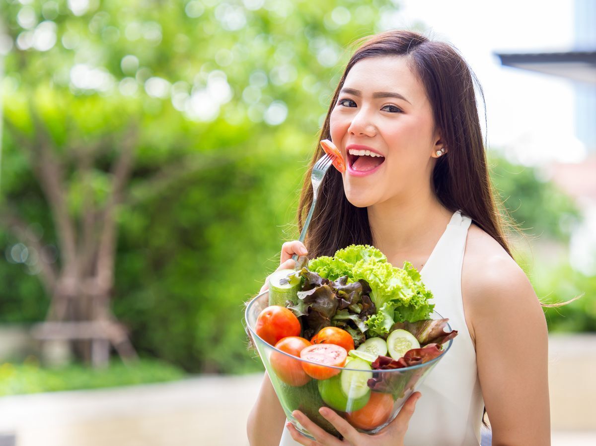 Asian woman eating a salad