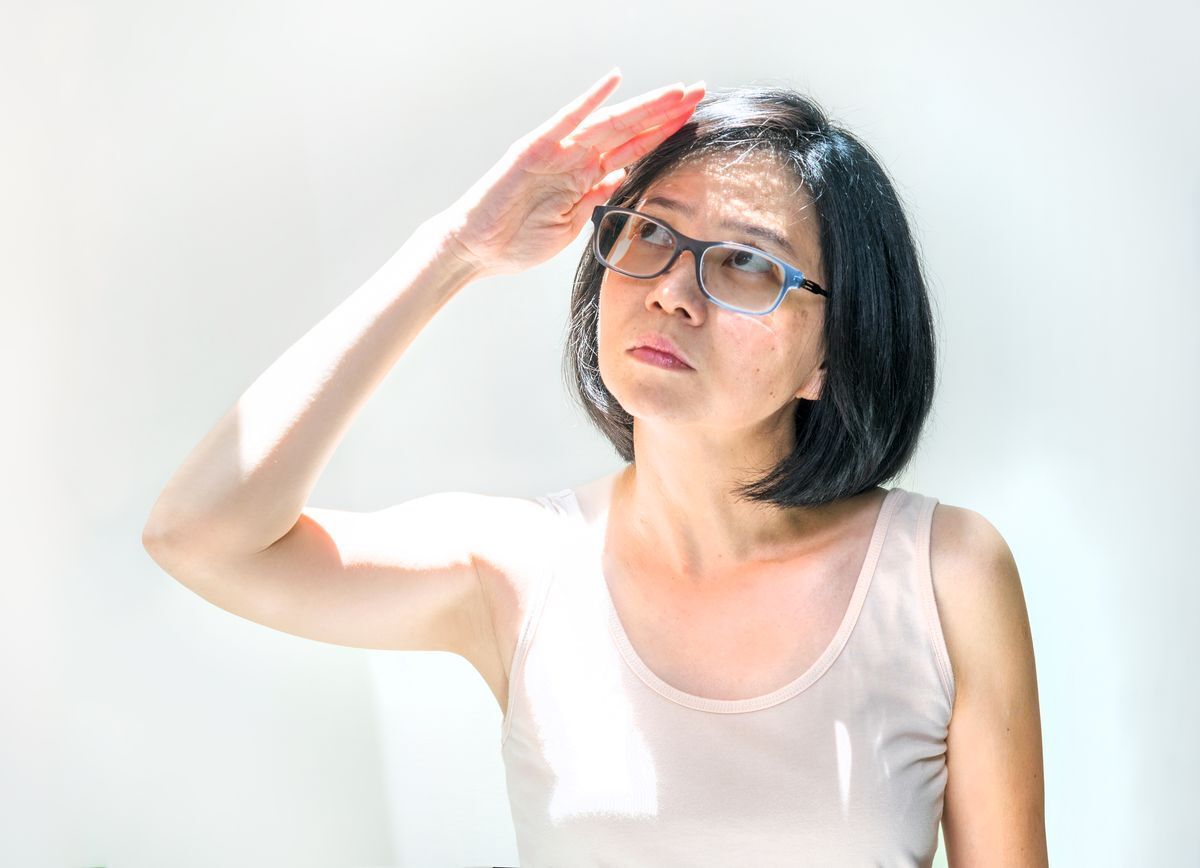 Asian woman shielding her face from the sun