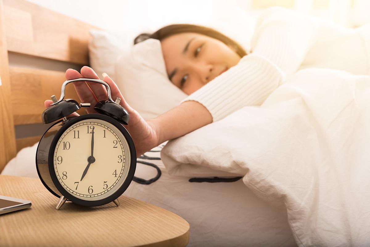 Asian woman pressing alarm clock