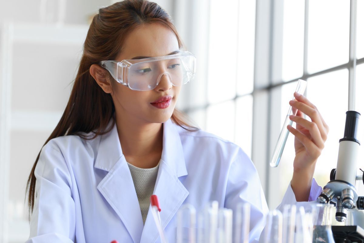 Asian woman holding a test tube in a lab.