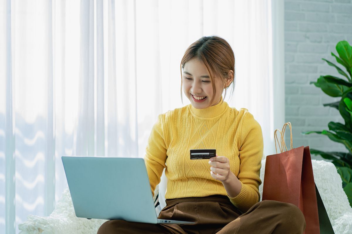 Asian woman shopping with a credit card on her laptop
