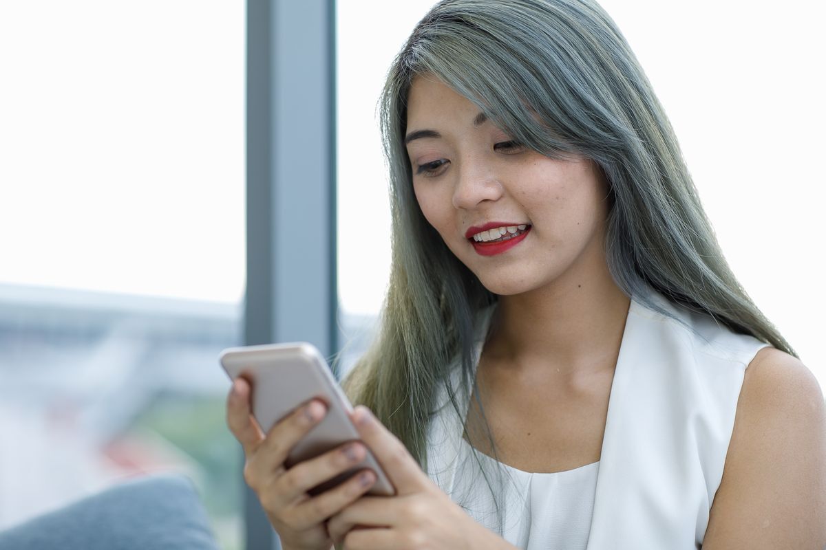 Asian woman with colored hair texting