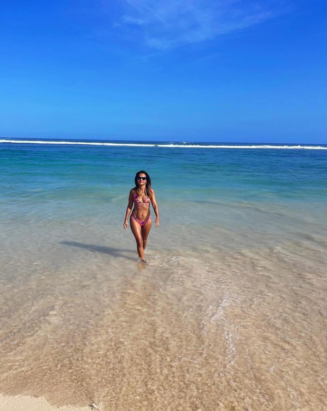 Asian woman in a bikini walking on the beach.