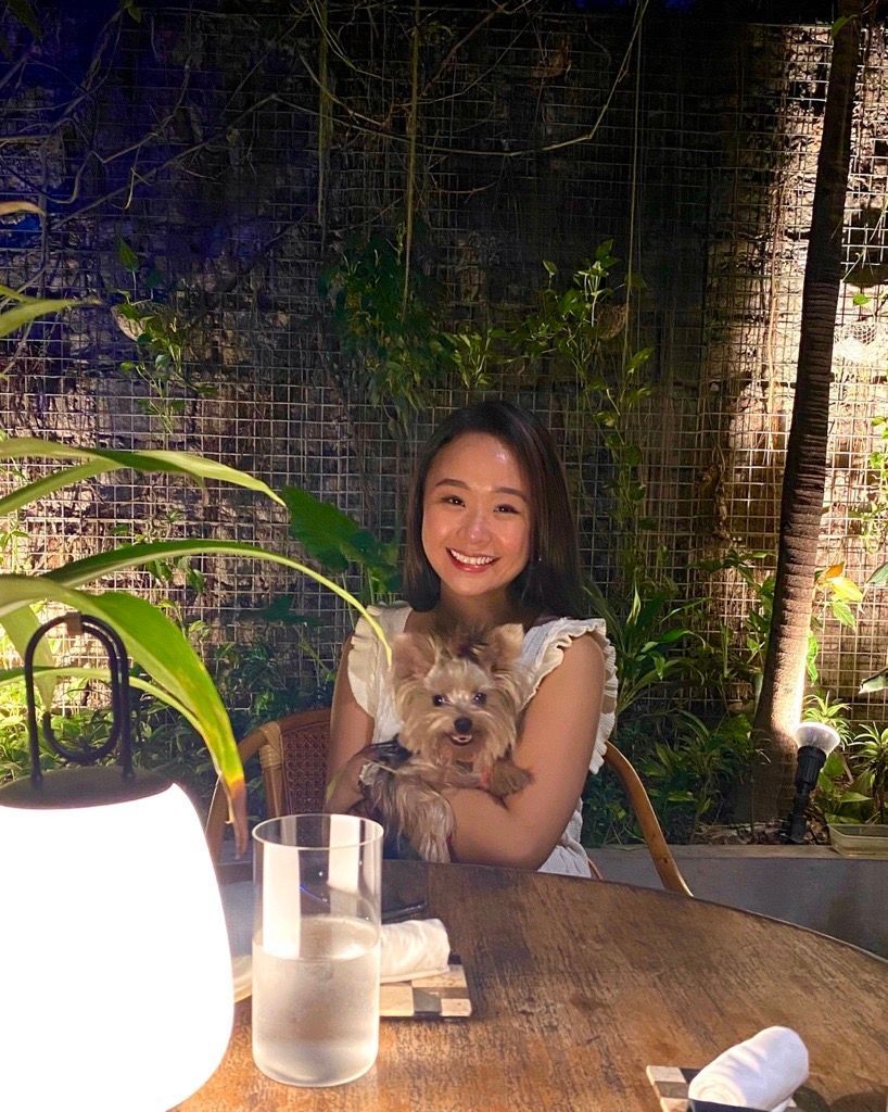Asian woman posing with her dog at a restaurant.