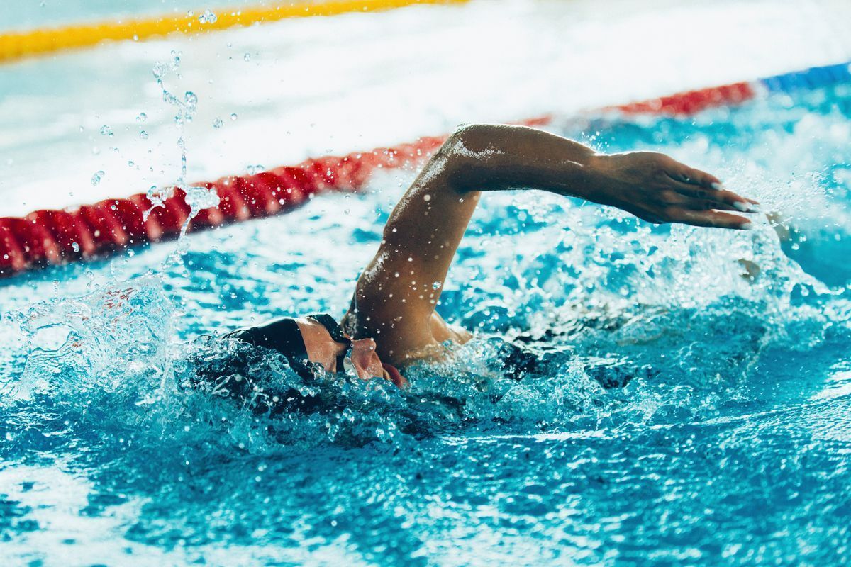 A man does the freestyle stroke in a swimming pool.