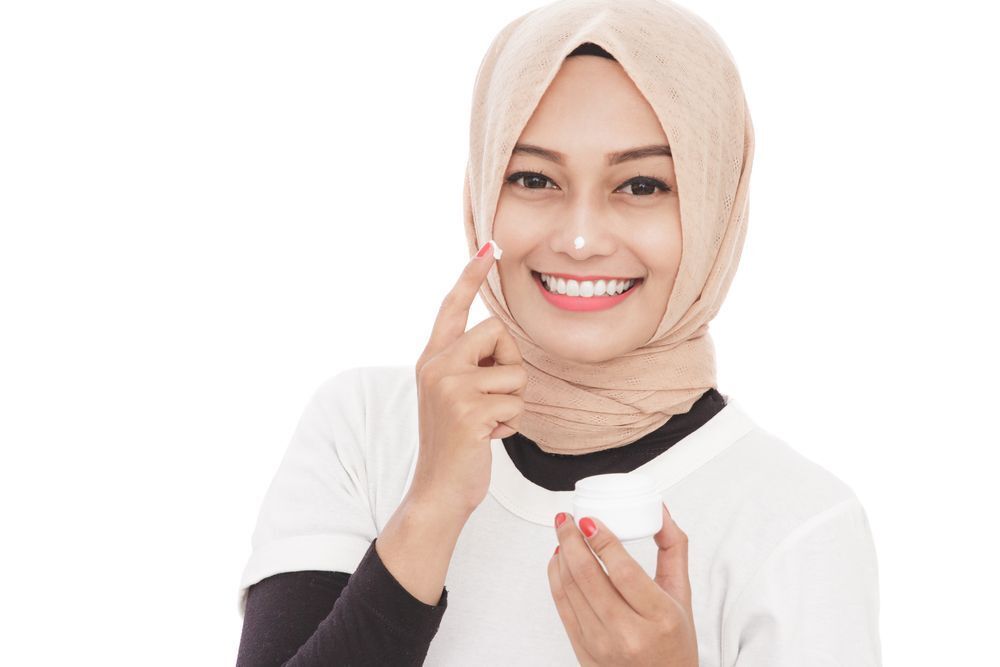 A beautiful hijabi woman wearing moisturizer