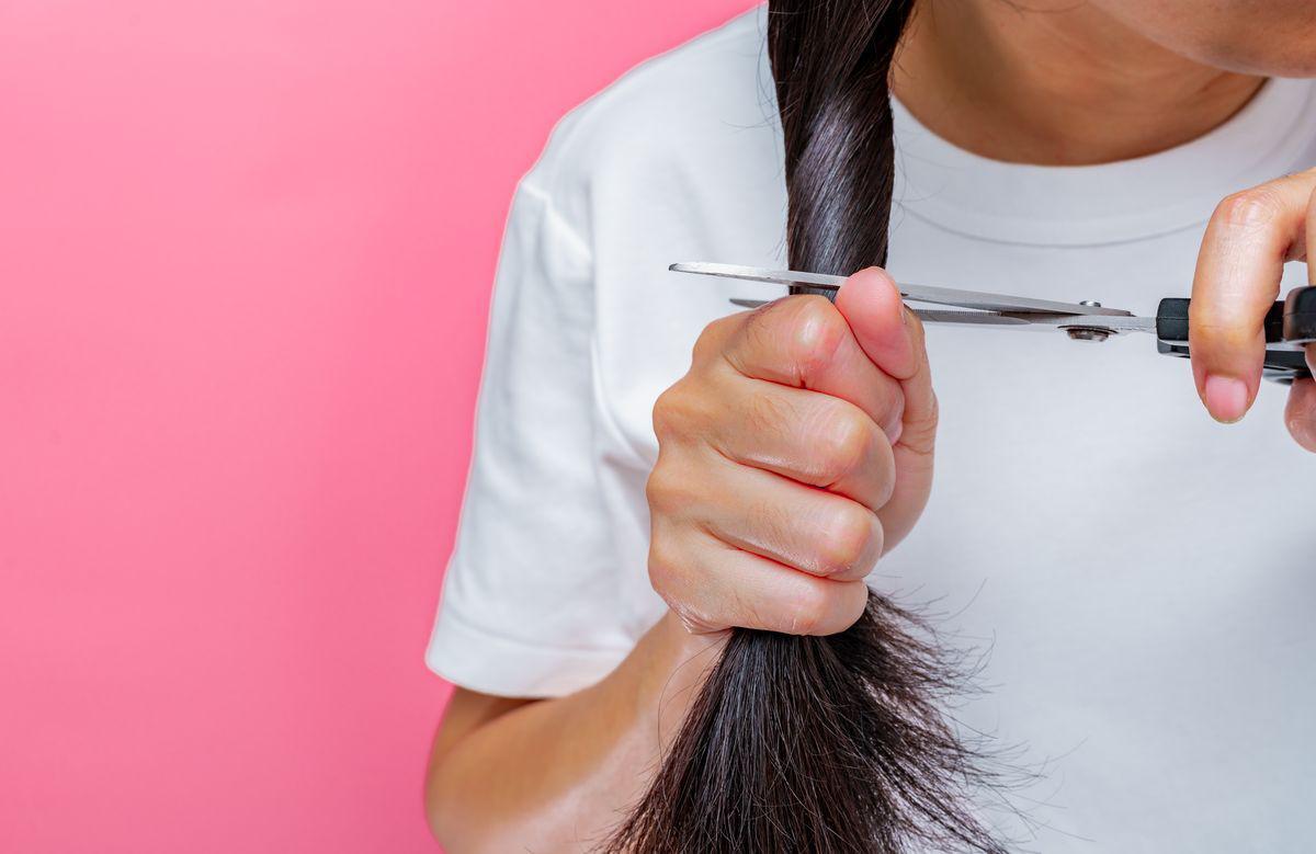 Woman cutting off damaged hair 