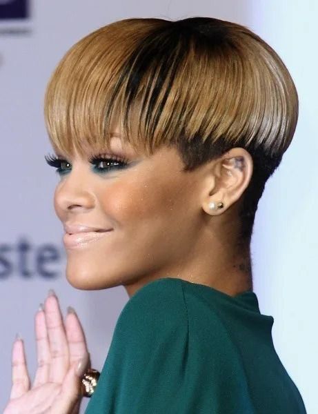 Rihanna with bleached bunot hair waving her hand on the red carpet.