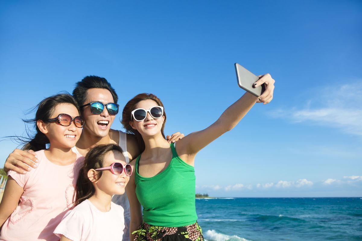 Family taking a group selfie while on vacation.