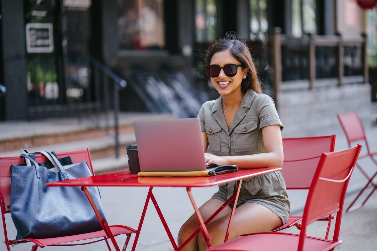 Asian woman wearing sunglasses while working al fresco