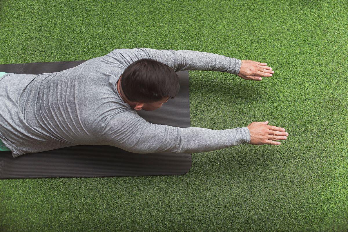 Man on mat doing superman abs exercise 