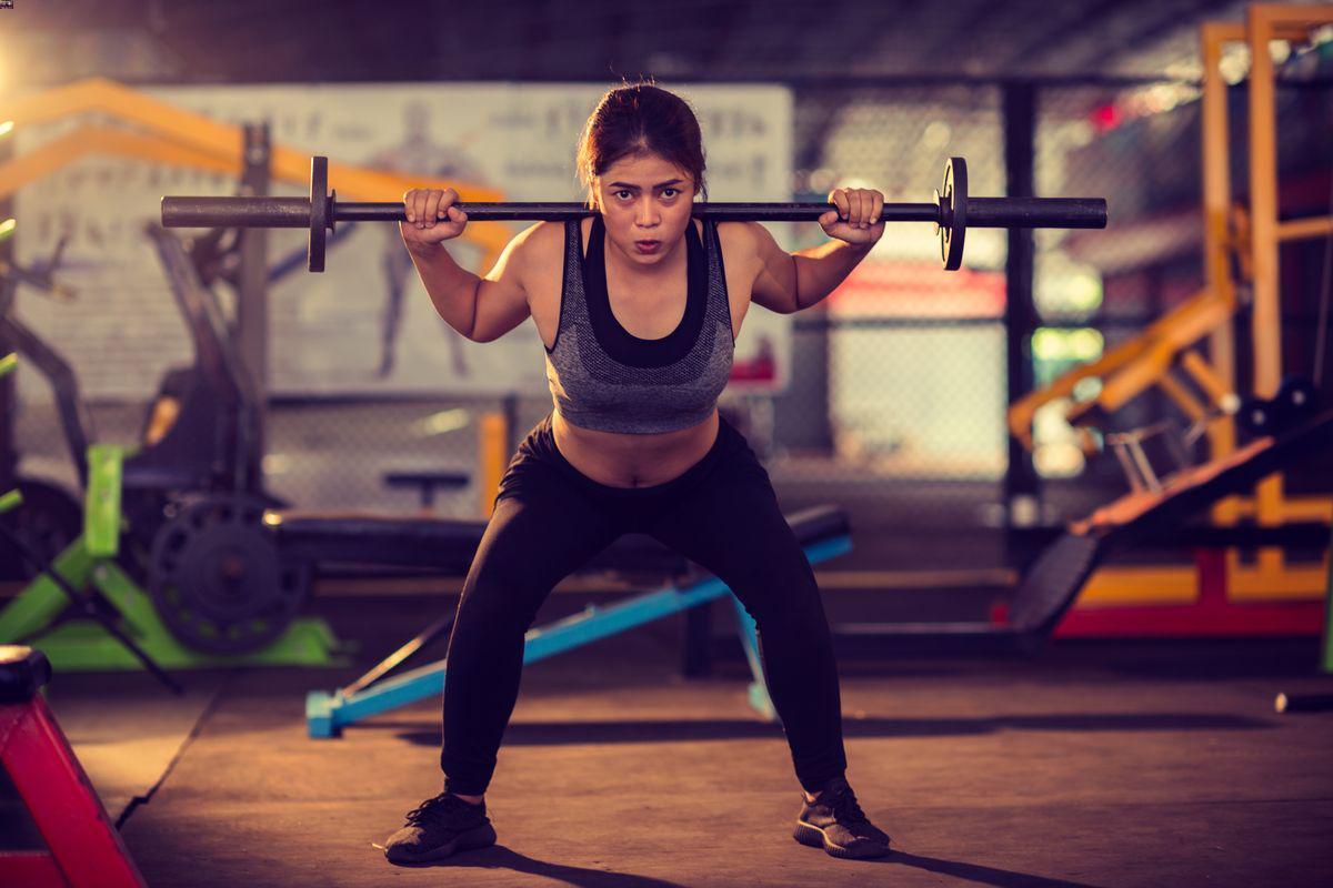 Asian woman lifting weights at the gym