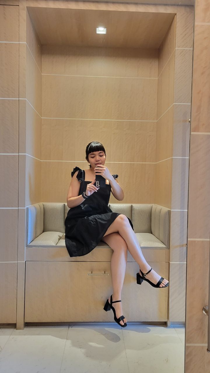 Woman sitting down and taking her photo in front of a mirror.