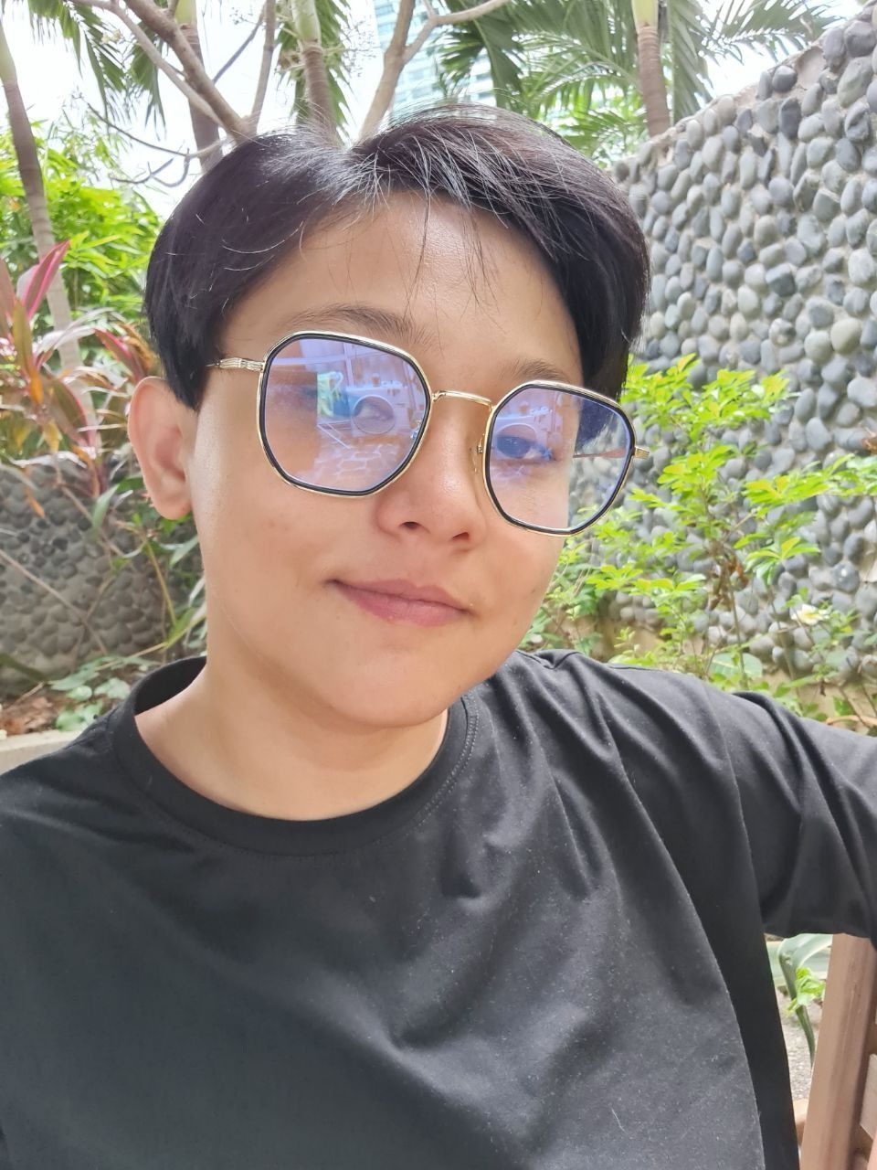 Half-body photo of woman, smiling and taking a selfie.