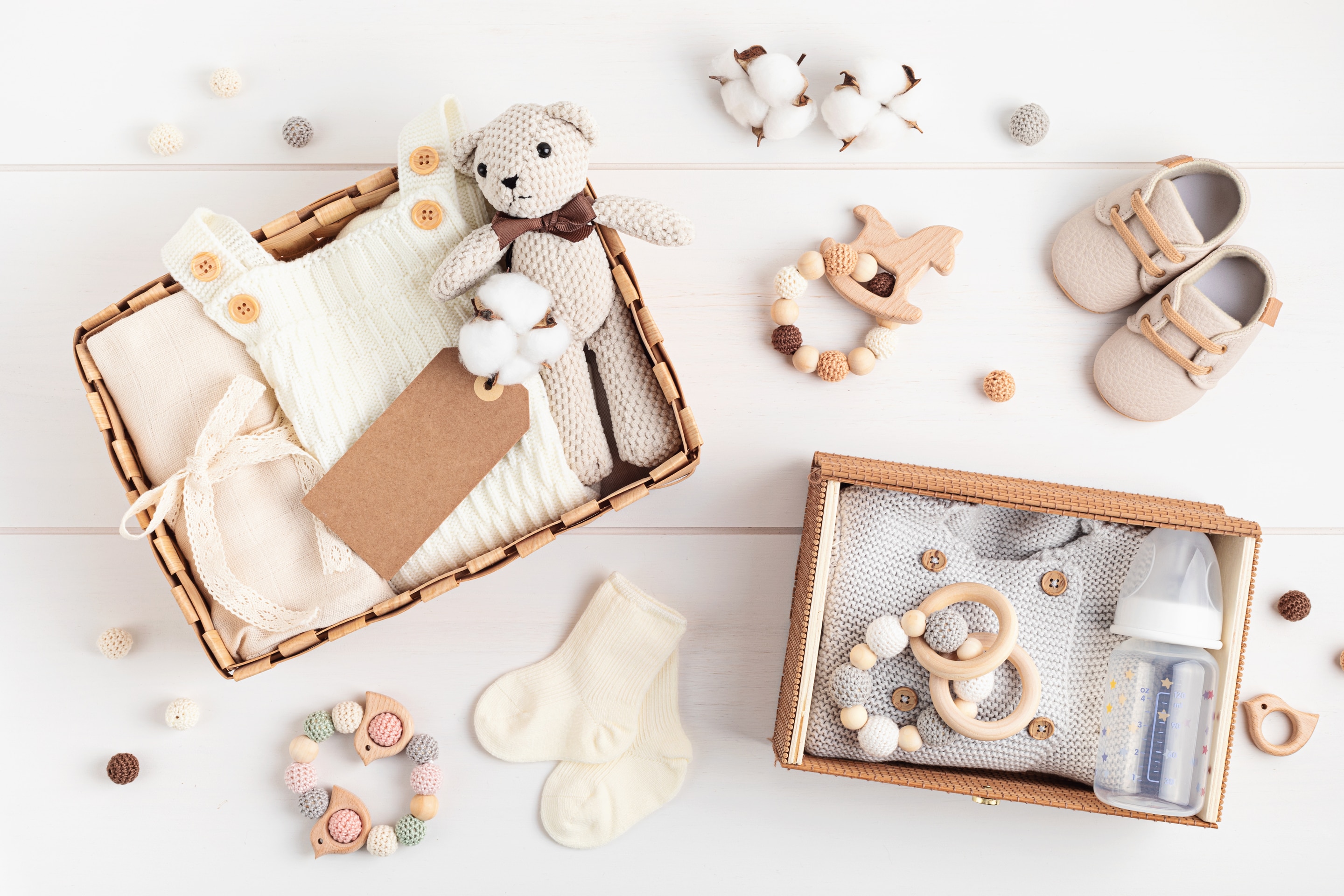 Kado untuk bayi baru lahir dalam keranjang hadiah berisi pakaian dan aksesori bayi berwarna netral