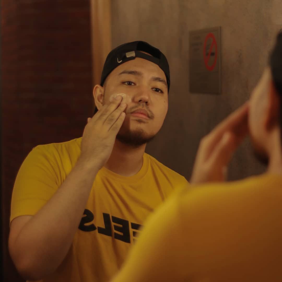 A man washing his face in front of the mirror.