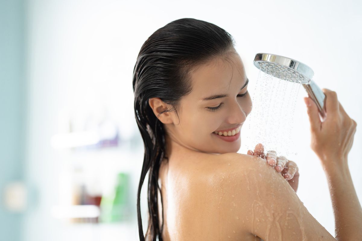 Asian woman smiling; enjoying a cool shower