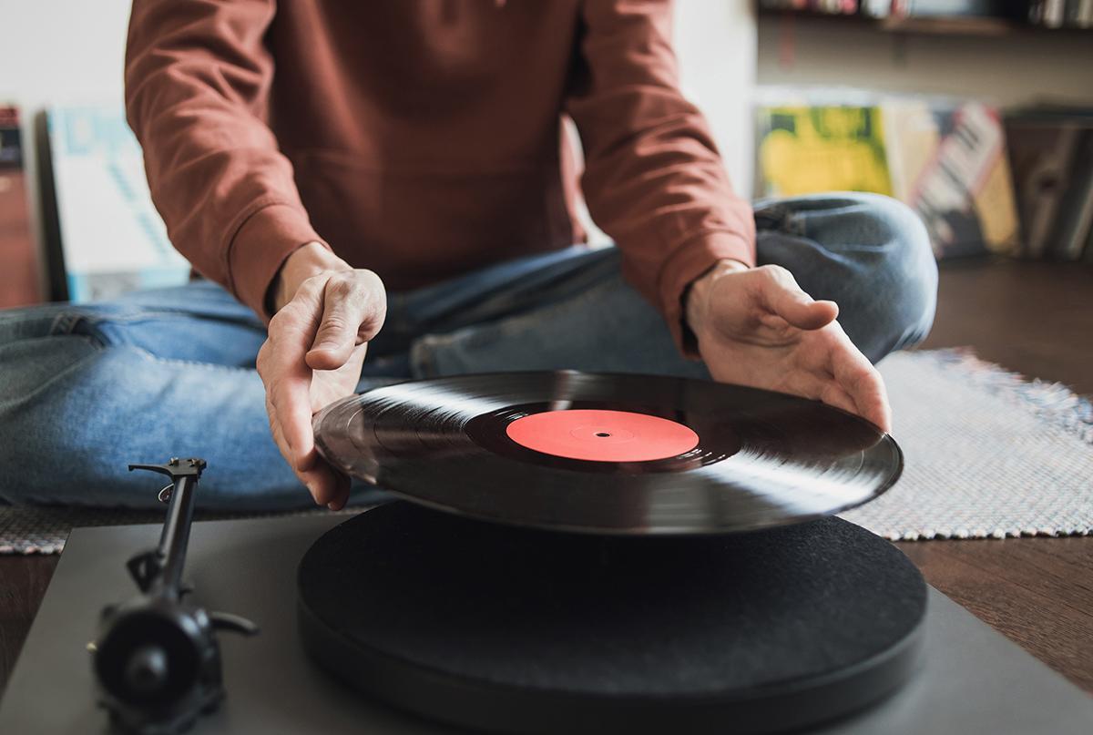 A young man places a record on his record player.