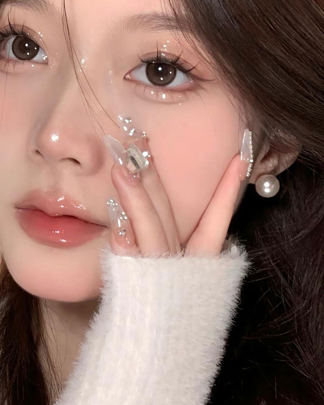 A closeup of woman wearing Douyin makeup with long manicured nails.