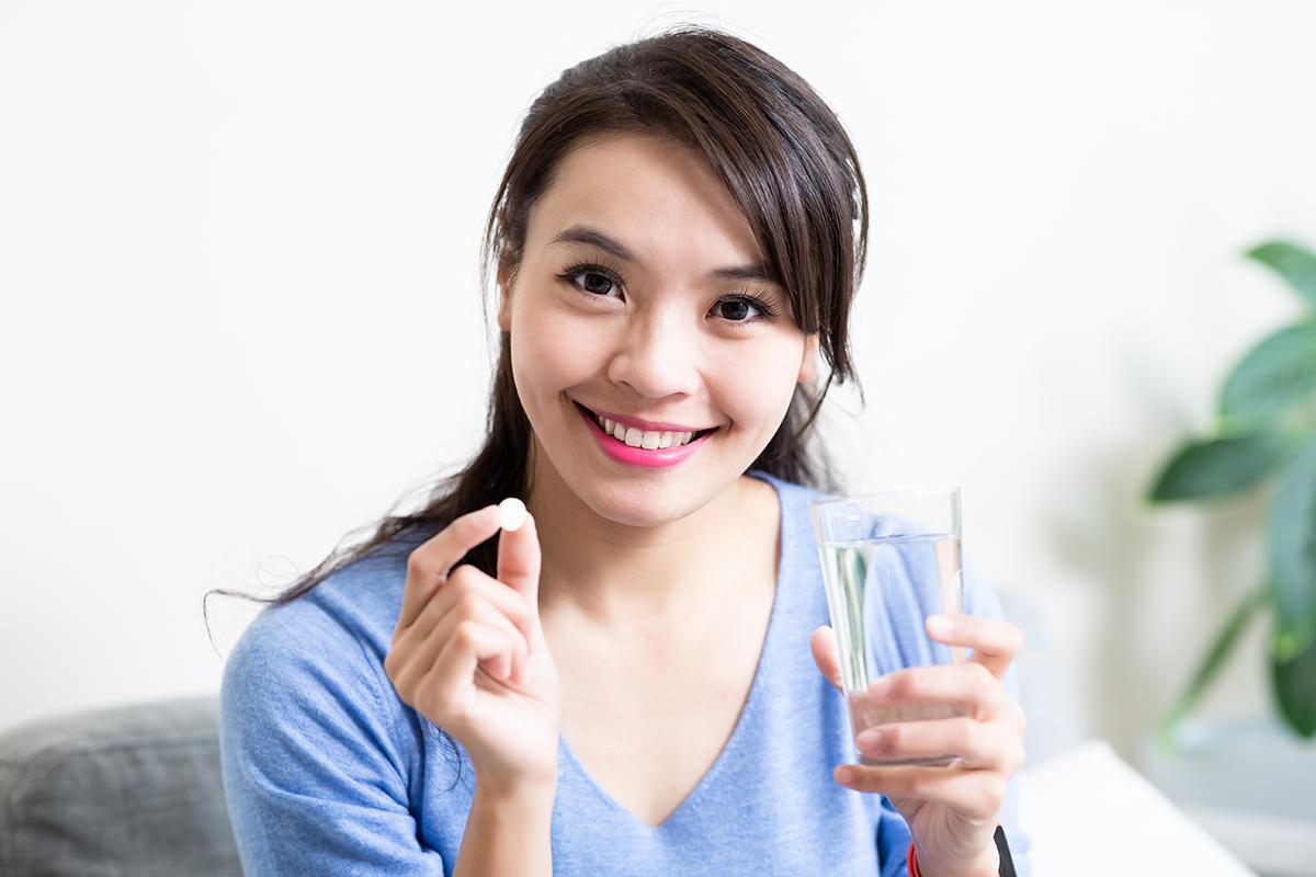 Smiling Asian woman holding tablet and water