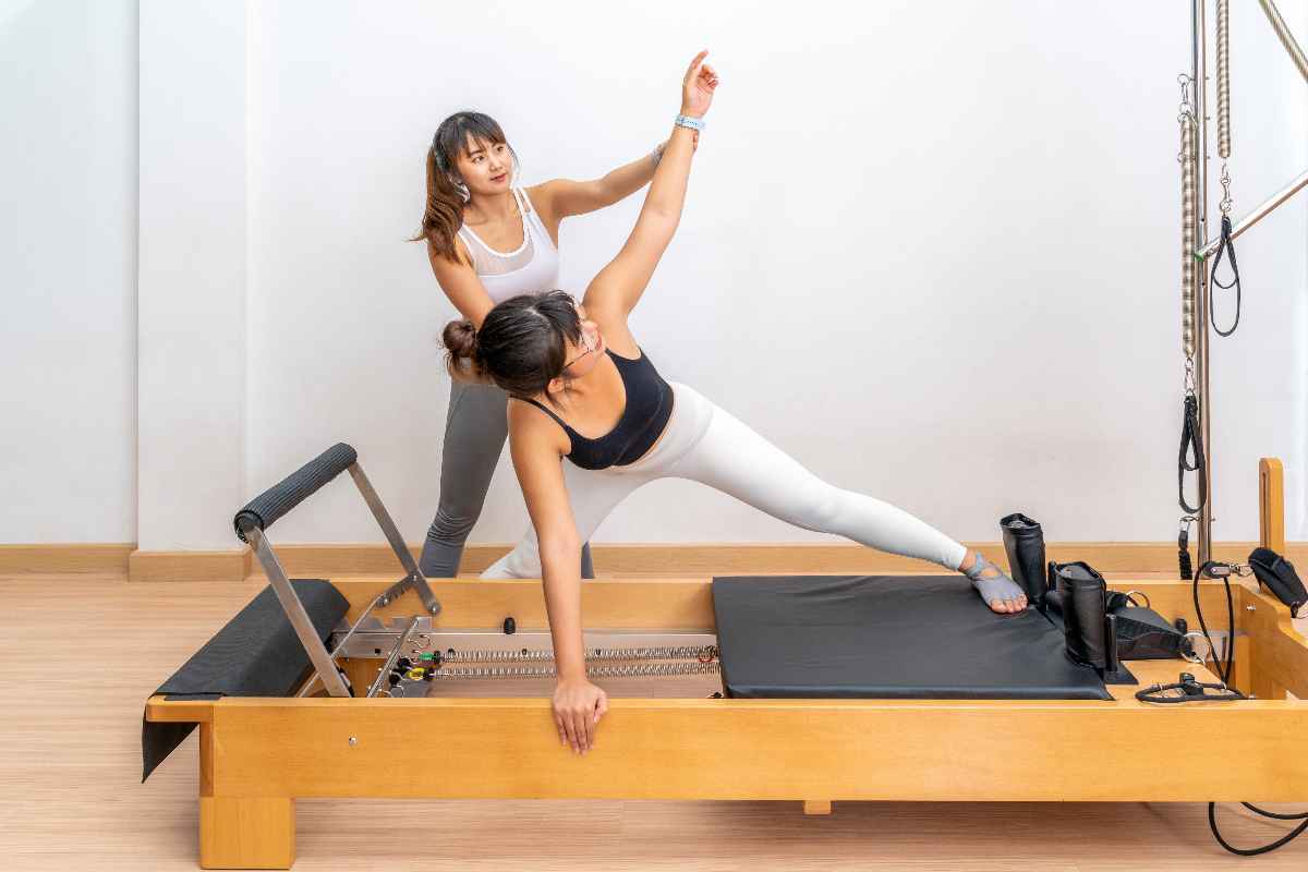 Asian woman doing a Pilates workout with an instructor. 