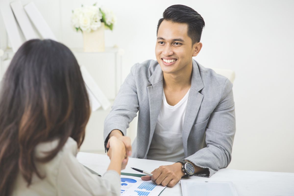 Young man is shaking hands with a woman in a professional setting.