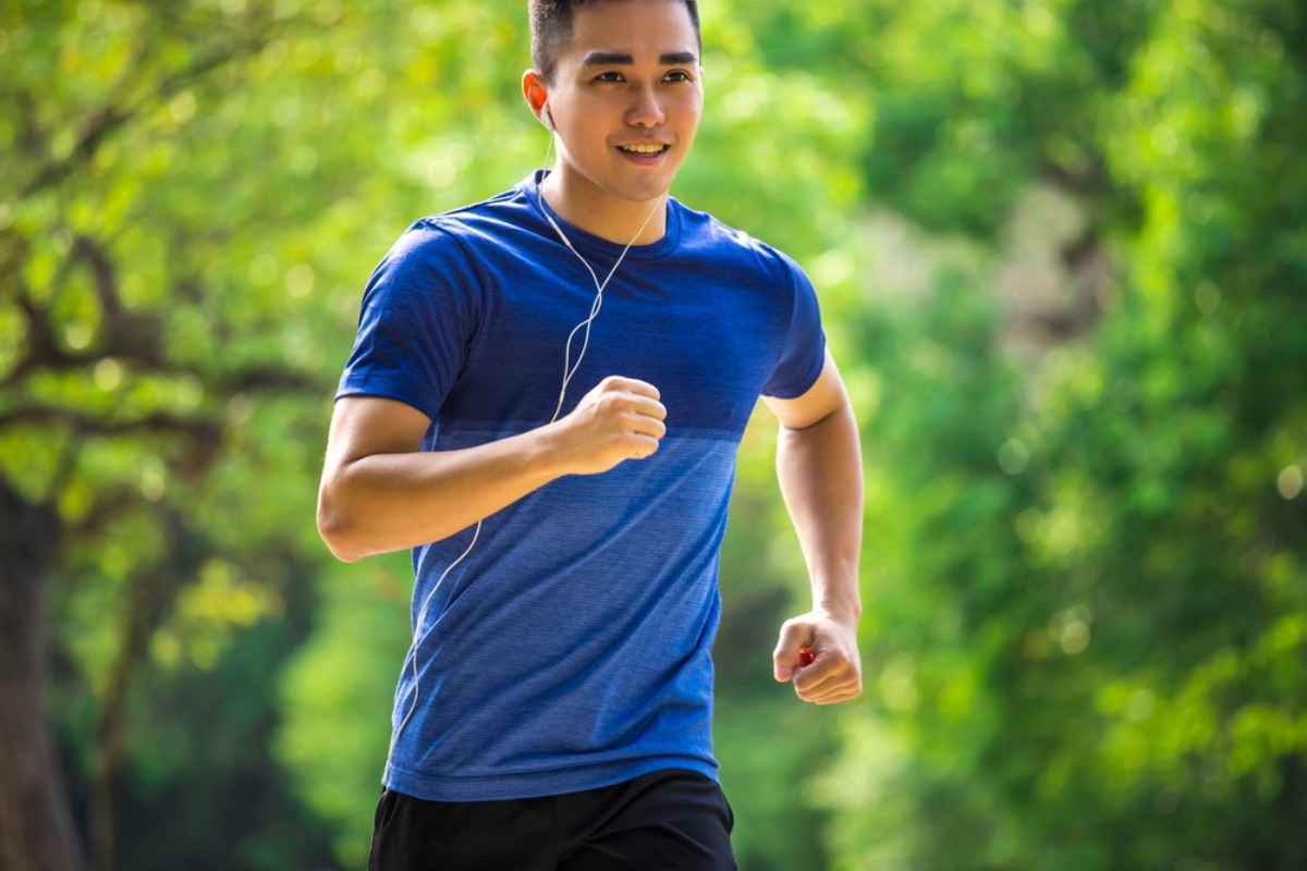 Man in blue shirt jogging at the park.