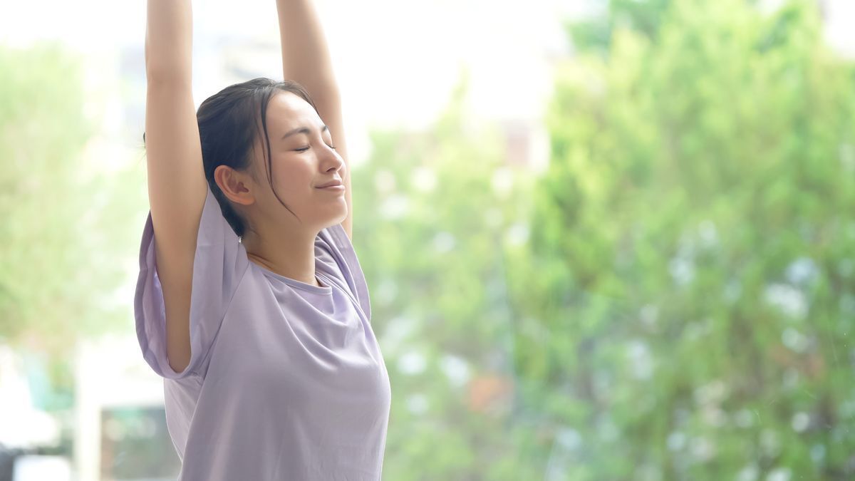 Woman in a lavender top stretching her arms.