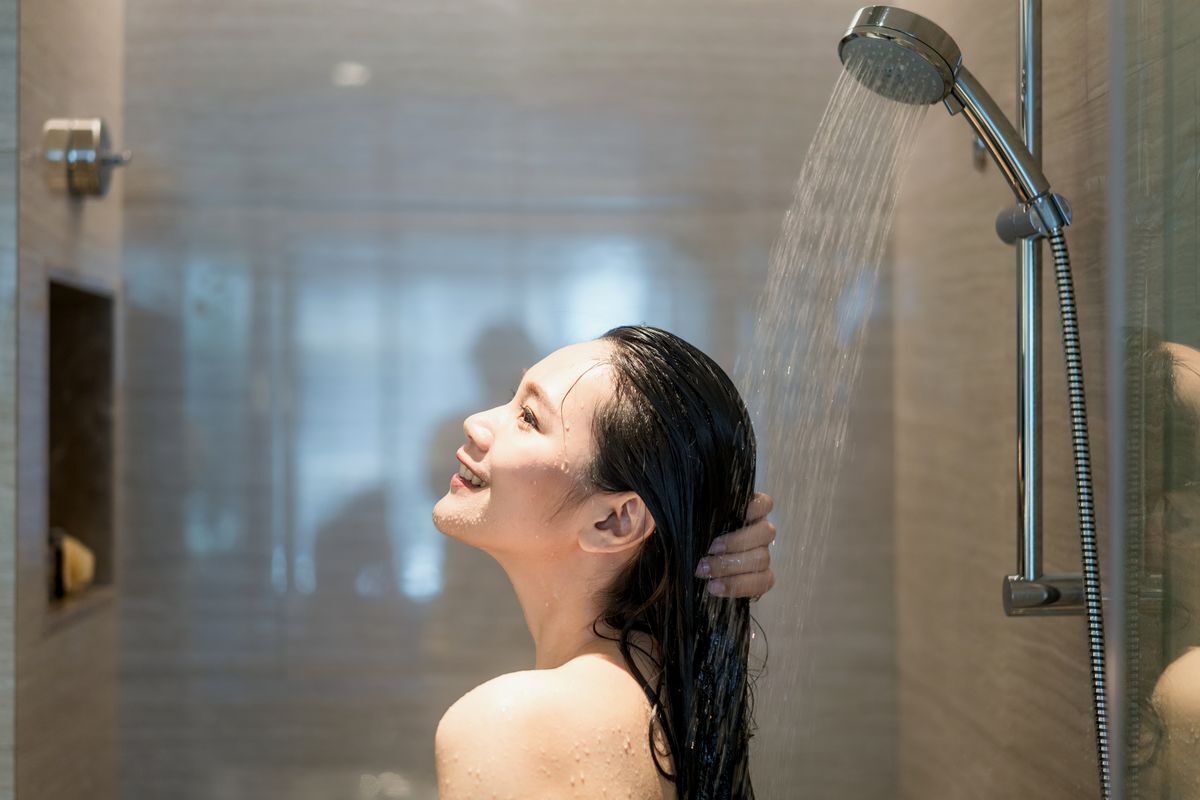 Woman washing her hair with water in the shower.