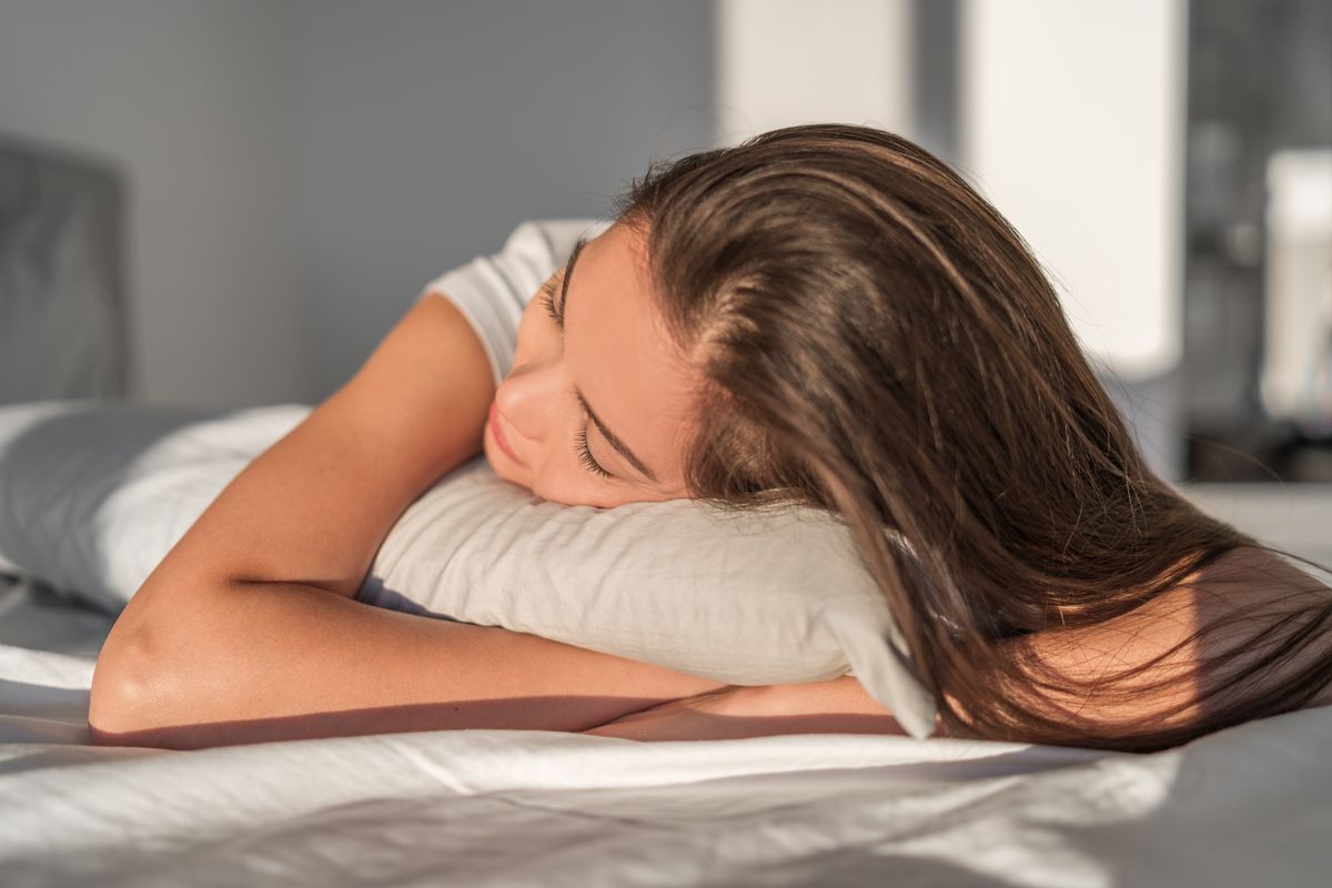 Woman with long, brown hair sleeping on a silk pillowcase.