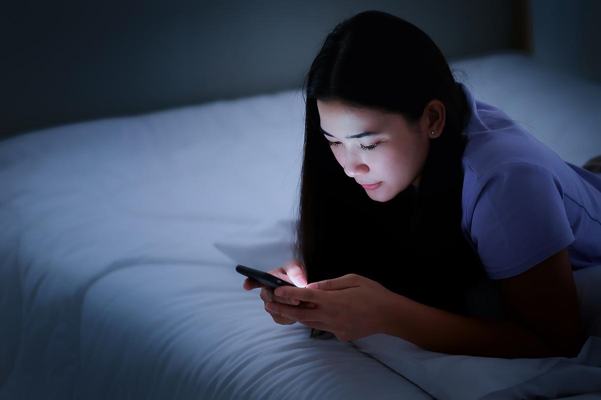 Woman in bed looking at phone