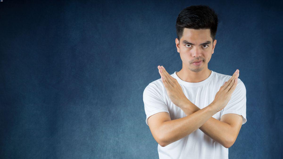 A man crossing arms to say no