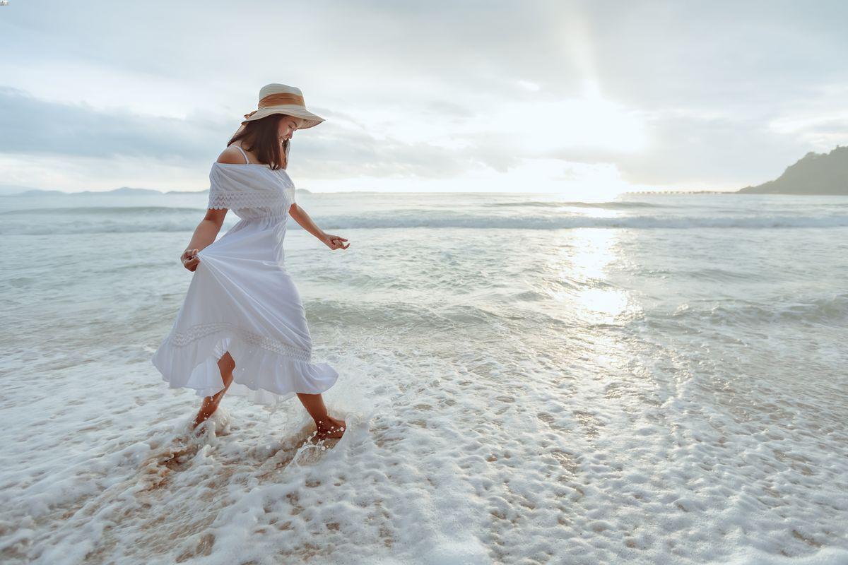 Asian woman wearing maxi dress on the beach.