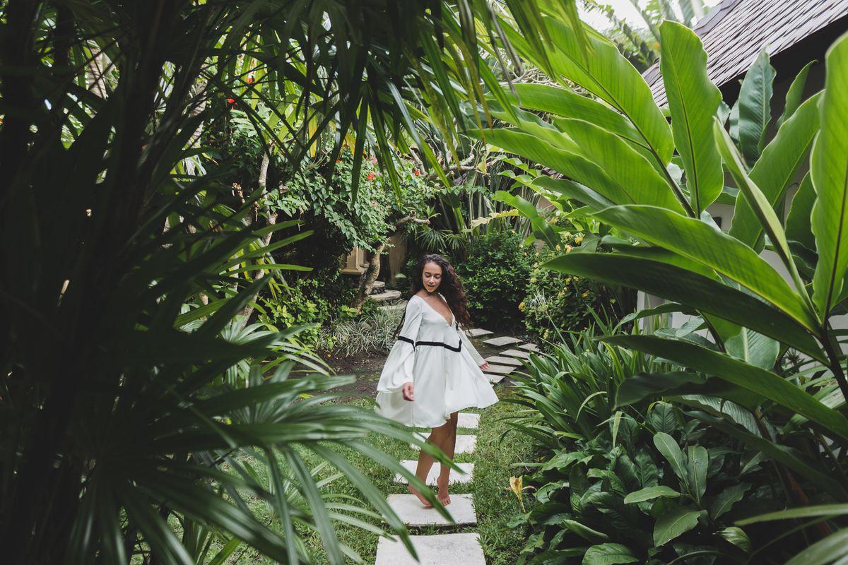 woman walking tropical garden white dress