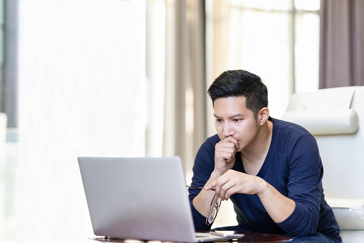  Asian man intently looking at his computer screen
