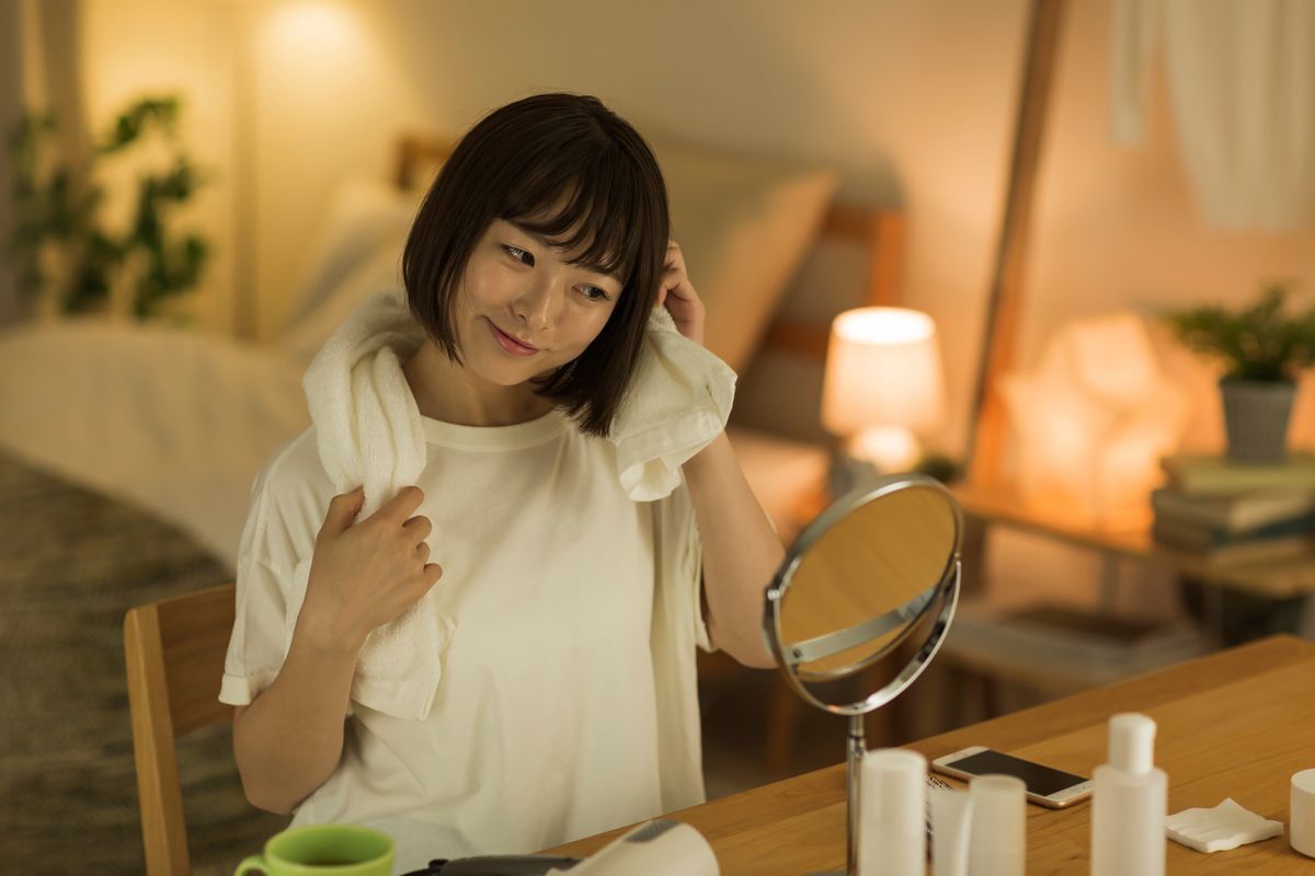 Young Asian woman drying her hair after taking a bath at night