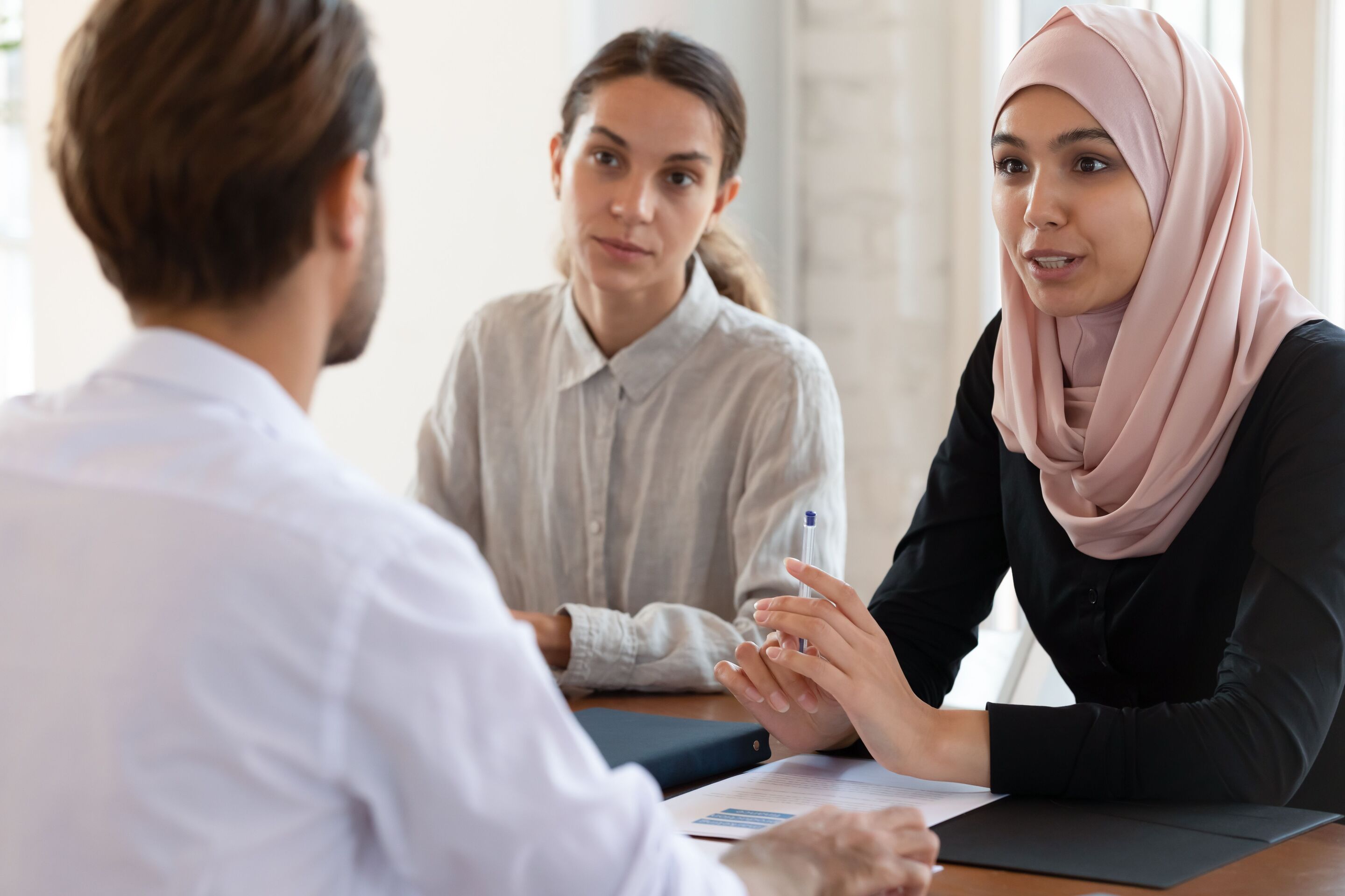 A woman in hijab talking to a male officemate