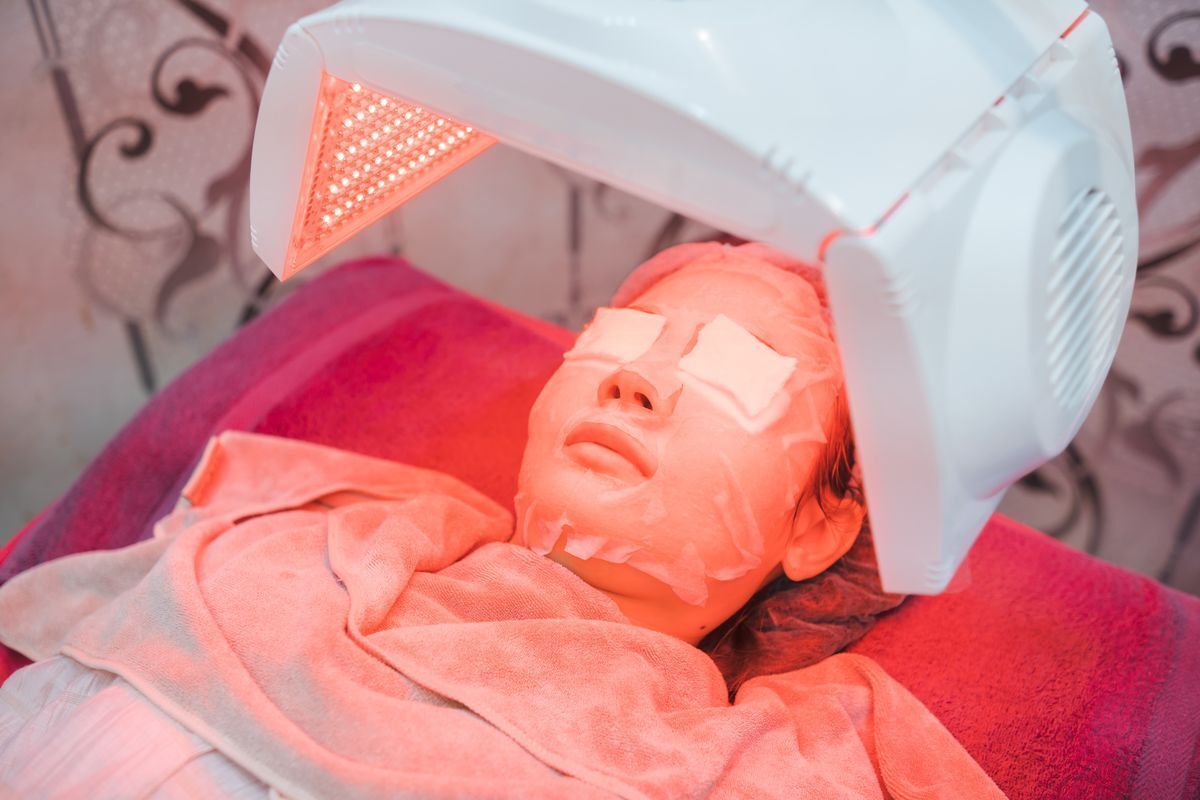 Woman getting red LED light treatment on her face. 