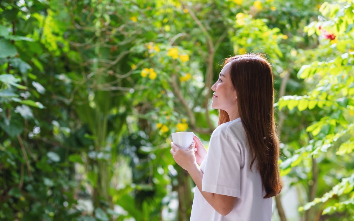 Woman relaxing and having coffee in a park.